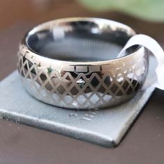 a close up of a ring on top of a piece of metal with a white ribbon