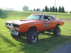 an orange muscle car is parked in the grass