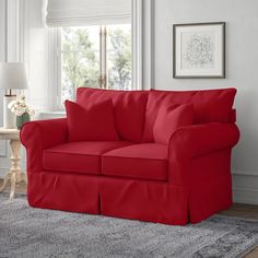 a red couch in a living room next to a window