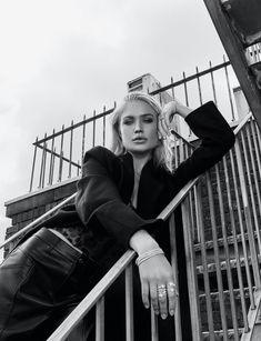 a woman leaning on the hand rail of an escalator in black and white