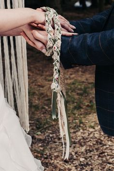 the bride and groom are holding each other's hands with ribbons attached to them