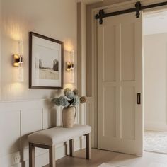 a white bench sitting in front of a doorway next to a wall with pictures on it