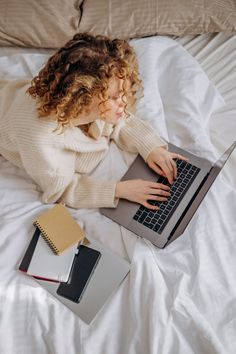 a woman laying in bed using a laptop computer