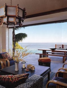 a living room filled with furniture and a large window overlooking the ocean in front of it