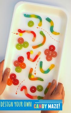 a child's hands holding up a tray with buttons on it and the words design your own candy maze