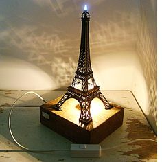 a lamp that is sitting on top of a wooden box with the eiffel tower lit up