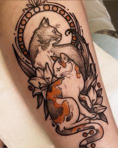 a tattoo with two cats sitting on top of each other and an orange fish in the middle