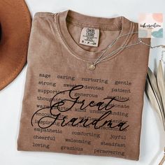 a t - shirt that says great grandma on it next to some feathers and a hat