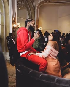 a man and woman sitting on a couch in front of a crowd