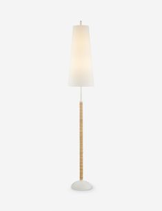 a floor lamp with a white shade on the base and a wooden stick in front of it