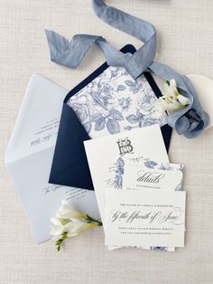 the wedding stationery is laid out with blue and white flowers, ribbons, and envelopes