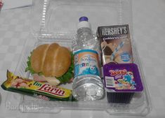 the lunch box contains a sandwich, milk, and candy