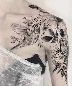 the back of a woman's shoulder with flowers and hummings on her arm