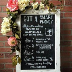 a chalkboard sign with flowers on it next to a brick wall that says, got a smart phone?