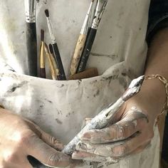 a person with paint on their hands and some brushes in the other hand while they are holding something