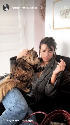 a woman sitting on a couch holding a cat