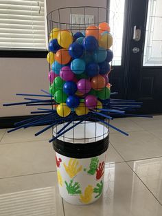 a bucket filled with balloons sitting on top of a tiled floor