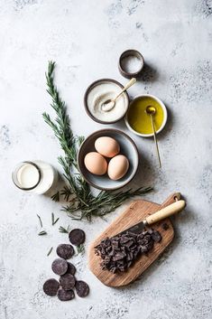 ingredients to make chocolate chip cookies laid out on a cutting board, including eggs and oreos