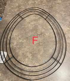 the letter f is placed on top of an empty circle with wire around it and a piece of paper next to it