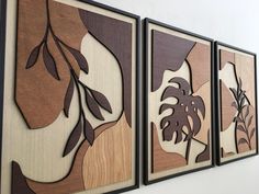 three wooden paintings hanging on the wall next to each other with leaves and plants painted on them