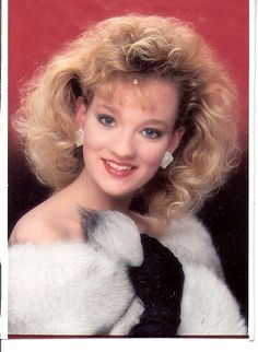 a woman with blonde hair wearing a black and white fur coat smiling at the camera