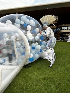 an inflatable ballon is on the grass with people inside it and one person standing next to it