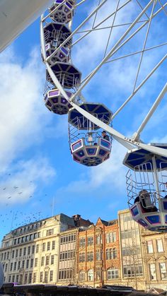 the ferris wheel is on display in front of some buildings and blue sky with white clouds