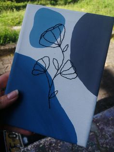 a person holding up a piece of art that has been painted with blue and white paint