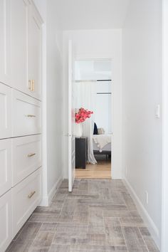 an empty hallway with white cabinets and wood flooring on the walls, leading to a bed