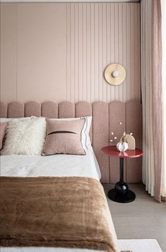 a bed sitting next to a window with pink walls and pillows on top of it