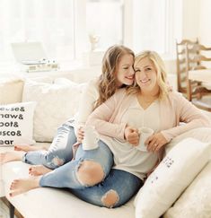 two women sitting on a couch hugging each other