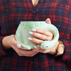 a woman in plaid shirt holding a green cup with her hands on the handle and wrist