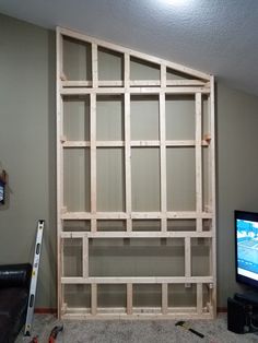 a tv sitting on top of a wooden shelf next to a wall mounted flat screen tv