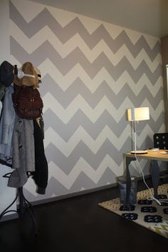 a room with a desk, chair and coat rack on the wall in front of it