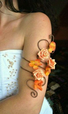 a woman with flowers on her arm is wearing a white top and orange bracelets