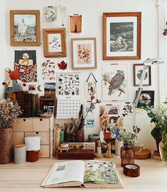 an open book sitting on top of a wooden table next to pictures and flowers in vases