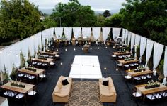 an outdoor seating area with couches, tables and lights on the side of it