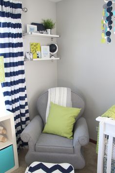 a baby's room with a gray chair and green pillows