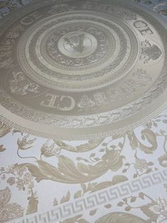 an intricately designed bed spread with gold and white designs on the bottom, along with a clock in the middle