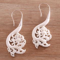 two pairs of white earrings on a wooden surface