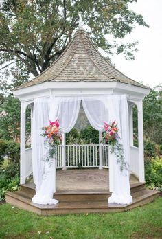 a white gazebo with curtains and flowers on it