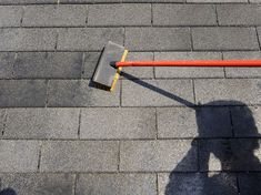 the shadow of a person standing on top of a roof next to an orange pole