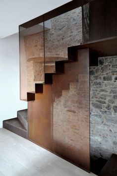 the stairs are made of wood and glass in this room with stone walls, white flooring and wooden steps