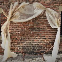 a brick wall with white drapes and some feathers hanging from it's sides