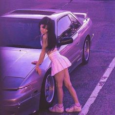 a woman leaning on the hood of a car