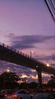 cars are driving on the road under a bridge at dusk with traffic lights and street lamps