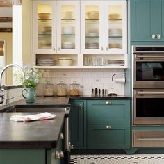 a kitchen with green cabinets and stainless steel appliances