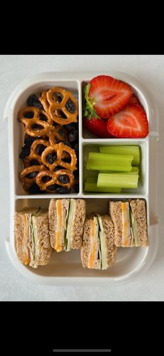 a lunch box with sandwiches, fruit and pretzels