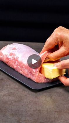 a person cutting up meat on top of a black plate with cheese and butter in front of them