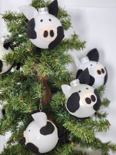 some ornaments are hanging from a tree with black and white animals on it's branches